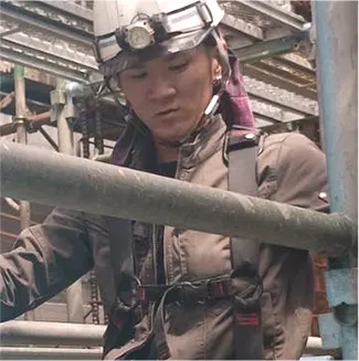 鉄筋の前で笑顔を見せる作業員